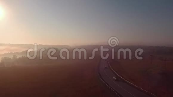 雾蒙蒙的日出和汽车的轮廓公路慢动作视频的预览图