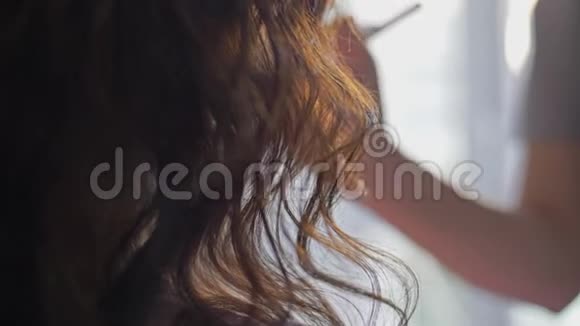 长长的卷发落在女孩的肩膀上美女化妆后景视频的预览图