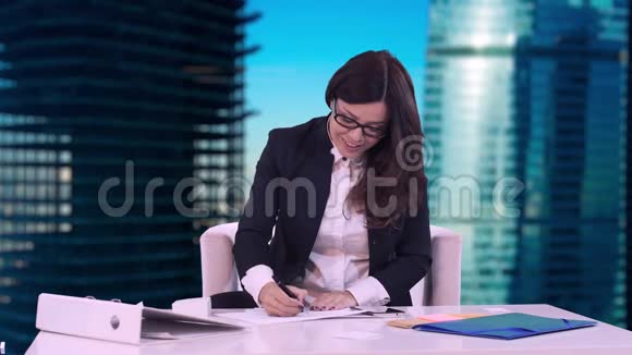 商务女性坐在办公室的办公桌前在文件上签名并交给经理背景是视频的预览图
