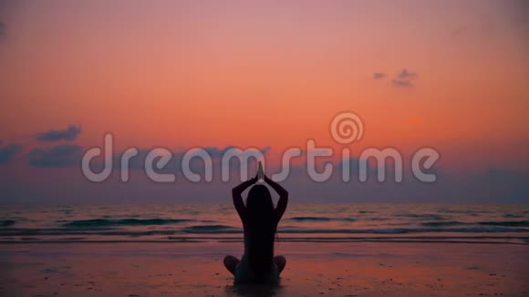 日落时分在海滩上练习瑜伽的年轻健康女性视频的预览图
