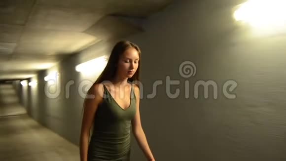 美丽的女人留着长发走在黑暗的街道上墙上有灯光视频的预览图
