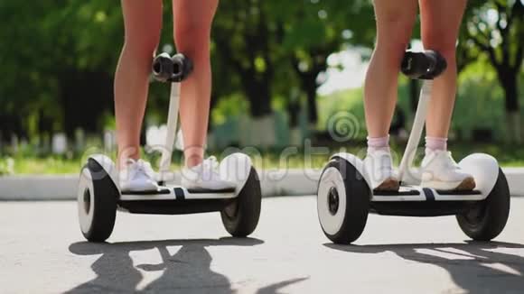 近距离观看后腿的女孩穿短短裤乘坐陀螺滑板车两个女朋友坐在公园里视频的预览图
