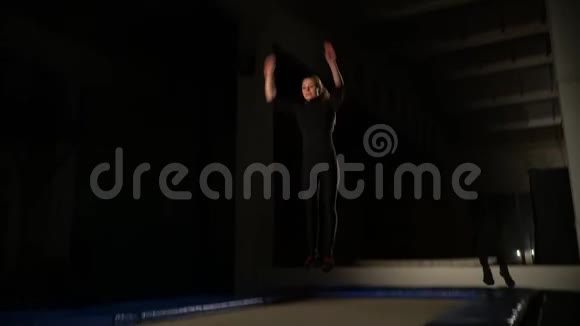 一个身材苗条的女人穿着紧身衣服跳在蹦床上做一个空翻动作缓慢视频的预览图