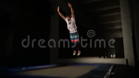 当一个人跳在蹦床上做一个筋斗时缓慢射击视频的预览图