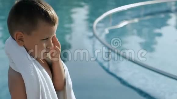 游泳池附近有白色毛巾的小男孩视频的预览图