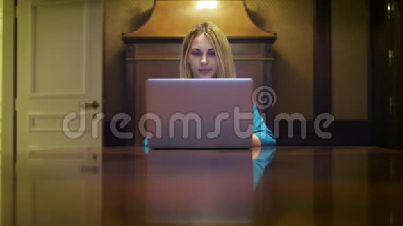一个严肃的女人坐在家庭工作室的桌子上写着笔记本电脑视频的预览图