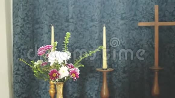 蜡烛和鲜花之间的木制十字架视频的预览图