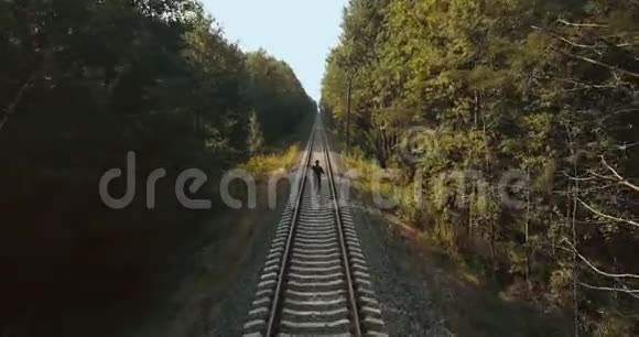 在铁路线之间奔跑的人无人机后视图在秋天的森林铁路上运动员奔向新的视角视频的预览图