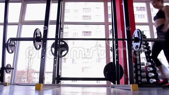 女运动员用沉重的杠铃向前弯曲女运动员在健身房锻炼视频的预览图