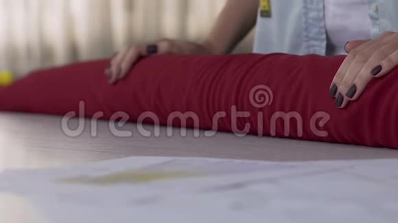 阿泰利埃的主人女人在桌子上滚动红色材料织物纺织品的选择视频的预览图