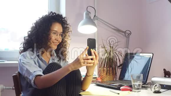 年轻的白种人微笑的女性坐在家里的电脑前视频的预览图