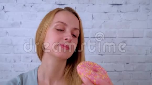 微笑的年轻女人吃甜甜圈喝咖啡视频的预览图