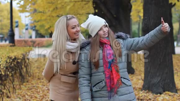 妈妈和女儿在一个美丽的秋天公园的背景下拍照视频的预览图