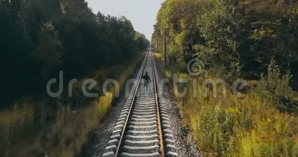 在秋林铁路上奔跑的人无人机后视图运动员在清晰视野的道路上一张电影照视频的预览图