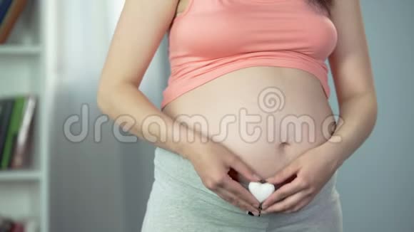 怀宝宝的快乐女士手里拿着心形纪念品怀孕视频的预览图