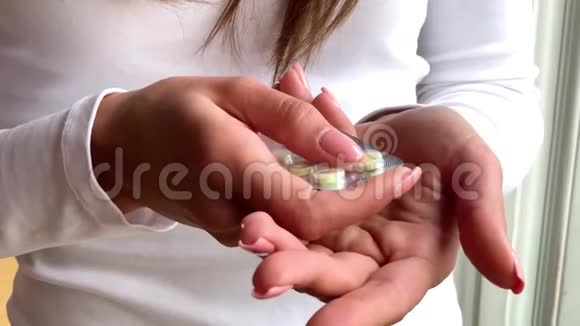 女人手从水泡包里拿药丸特写女性手倒白圆片手中的药物剂量药丸视频的预览图