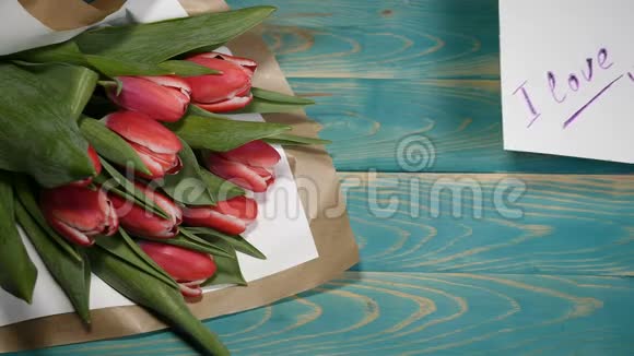 一张我爱你的留言条和郁金香花束在木桌上的俯视图夫妻关系的概念圣士视频的预览图