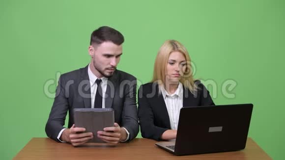 年轻的商业夫妇一起使用数码平板电脑和笔记本电脑视频的预览图