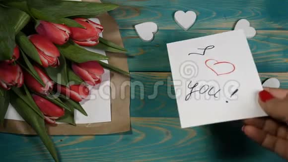 一张我爱你的留言条和郁金香花束在木桌上的俯视图恋爱关系的概念圣士视频的预览图