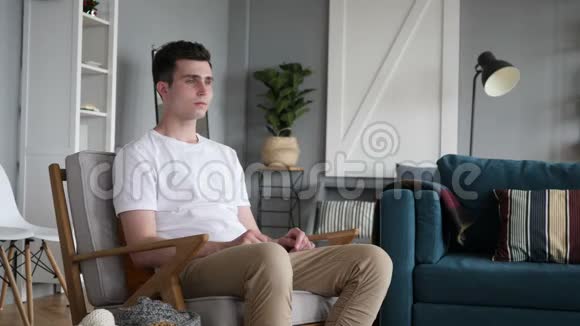 背部疼痛的男人坐在沙发上视频的预览图