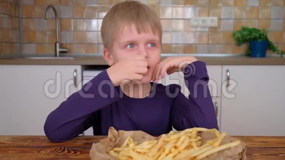 可爱的小男孩在厨房里享用炸薯条视频的预览图