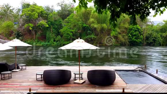 泰国葵坎查纳布里河附近度假胜地的海滨木筏上的躺椅或日光浴床和雨伞视频的预览图