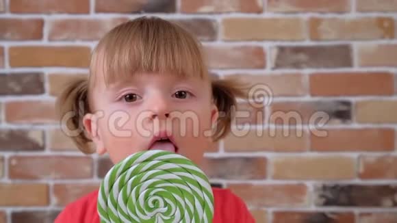 带绿色大棒棒糖的可爱小女孩的特写镜头视频的预览图