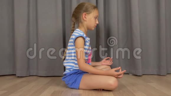 年轻女孩坐在禅坐在客厅的地板上打坐女孩练习瑜伽视频的预览图