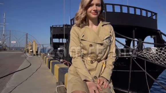 迷人的年轻金发女人在海沟与老式西装是坐在游艇码头和点在海上黑暗视频的预览图