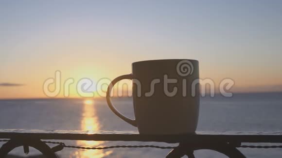 阳光明媚的早晨女性手在海边端起一杯咖啡视频的预览图
