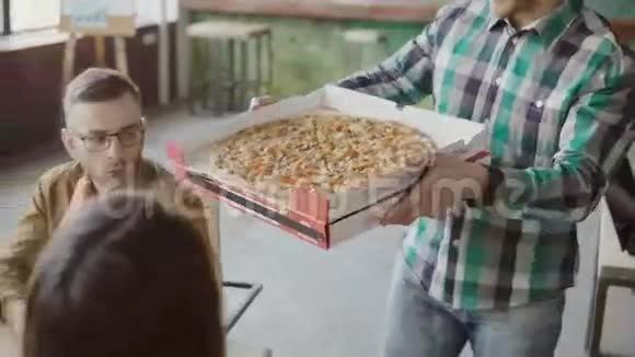 年轻的商人给现代办公室的混合种族团队带来披萨快乐的一群人在鼓掌和微笑视频的预览图