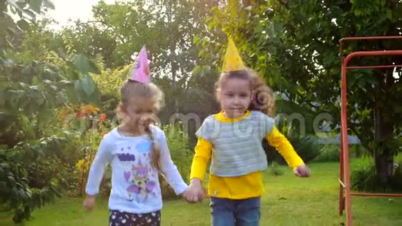 两个快乐漂亮的小女孩牵着手在新鲜空气中玩耍视频的预览图