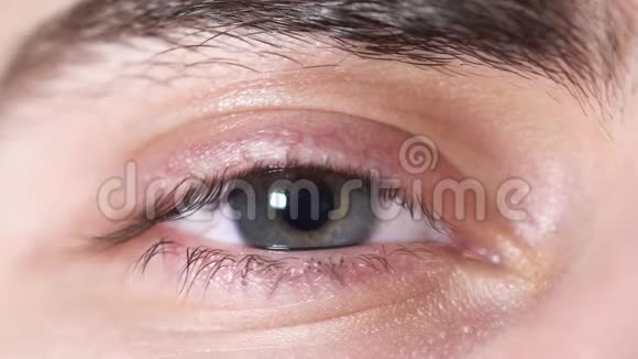 人类眼睛的特写年轻男子美丽的眼睛瞳孔从光中缩小人眼灰褐色有阴影视频的预览图