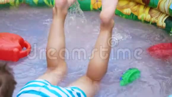 脚的特写一个四岁的男孩躺在孩子们充气游泳池里溅起水花溅起水花视频的预览图