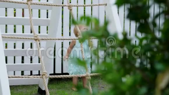 夏天在花园里孩子一个一岁的女孩要在操场上爬上孩子们楼梯家庭视频的预览图