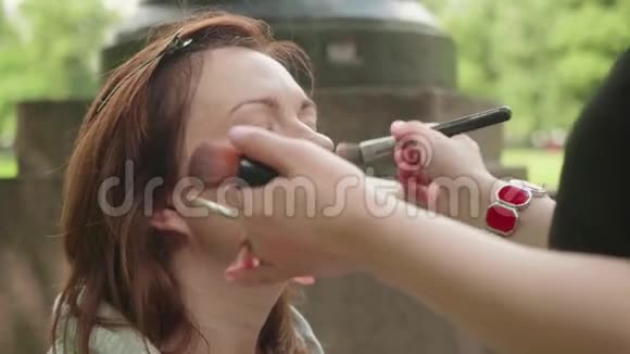 化妆师在摄影前应用粉调和女孩肤色慢动作视频的预览图