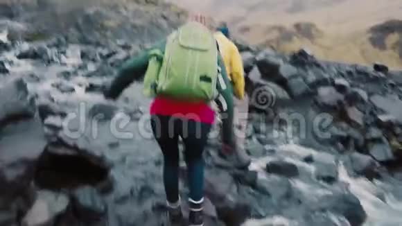 朋友们一起在山上远足的后景一群年轻人穿过河边的岩石视频的预览图