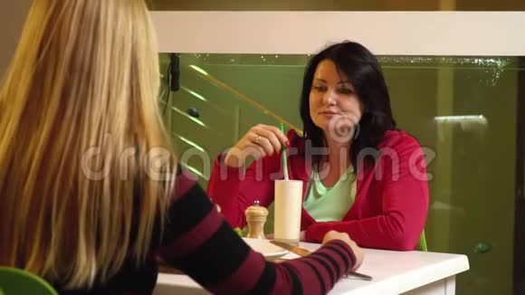 两个女人坐在水族馆附近的咖啡馆里聊天慢动作视频的预览图