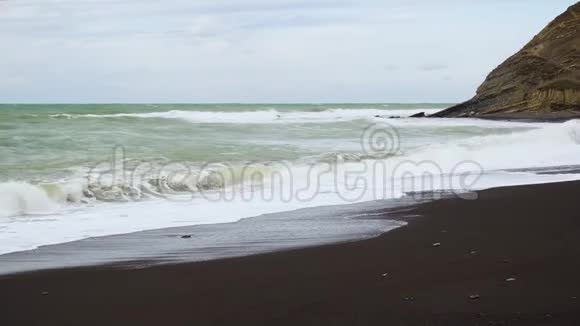 海岸上的黑色小沙和岩石视频的预览图