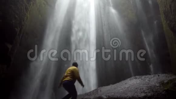 年轻的旅行者走在冰岛强大的Gljufrabui瀑布附近男性跳跃的喜悦和快乐视频的预览图