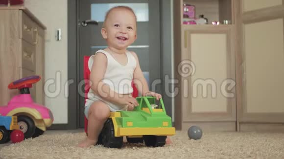 可爱的小男孩在家里地板上玩一个大汽车玩具小孩子在室内玩玩具车未来司机视频的预览图