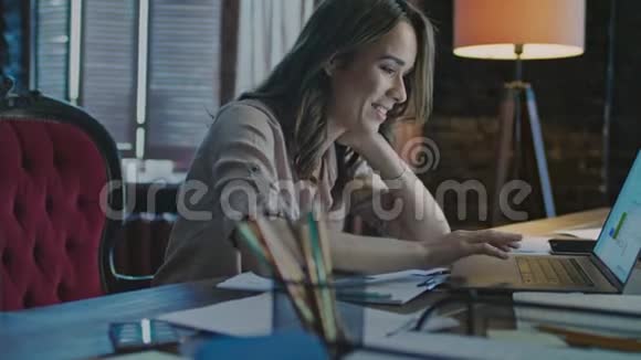 漂亮的女人在舒适的办公室工作微笑的女人在看手提电脑视频的预览图