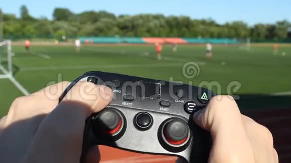 一个男人带着游戏操纵杆踢足球在体育场的背景下和真正的人一起踢足球视频的预览图