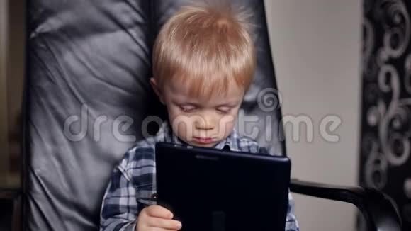 可爱的婴儿在皮椅上玩平板电脑视频的预览图