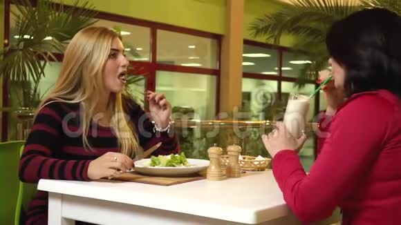 金发女郎在健身俱乐部咖啡厅吃素沙拉并与她的教练沟通视频的预览图