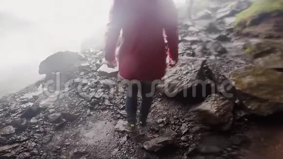 雨天爬山的年轻旅游妇女的后景女性探索新的地方慢动作视频的预览图