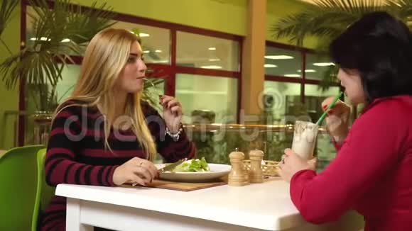 两个运动女人坐在健身俱乐部的餐厅里在吃零食的时候聊天视频的预览图