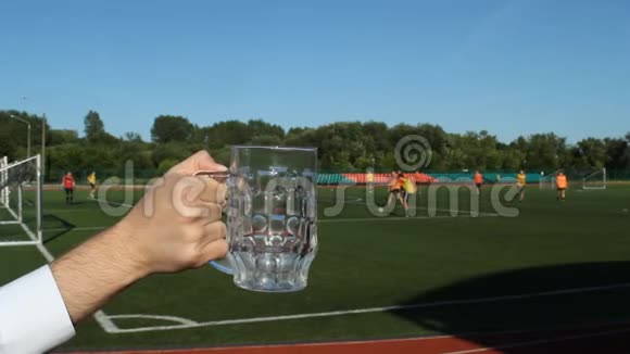 在足球场的背景下一个男人在杯子里倒啤酒视频的预览图