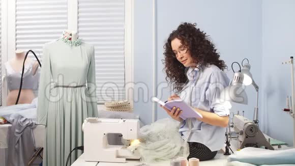 女裁缝在笔记本上书写织物的长度和宽度视频的预览图