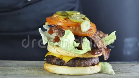一个大汉堡和一个蔬菜和一个芝麻面包的双切口形成一个汉堡的过程厨师在视频的预览图